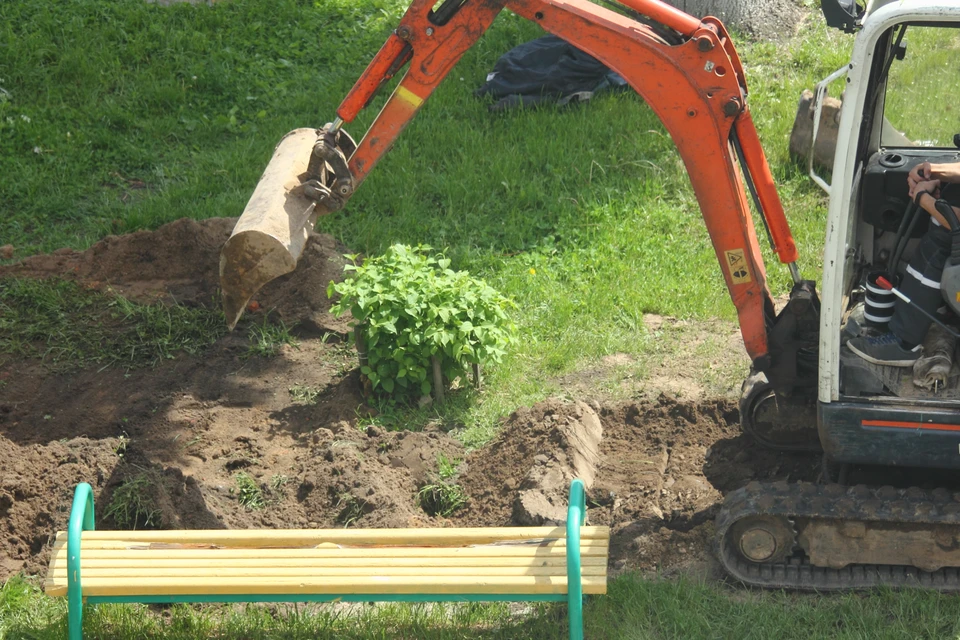 Chantier extérieur d'aménagement paysager avec pelleteuse orange effectuant des travaux de terrassement